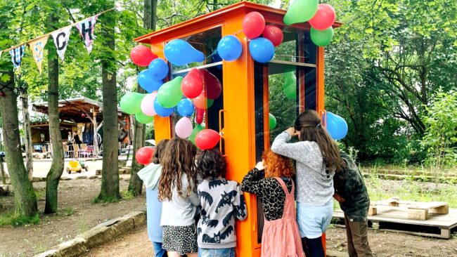 Die Kinder drücken sich die Nasen an den Schreiben des Bücherschranks platt. Foto: Kinderladen e.V.