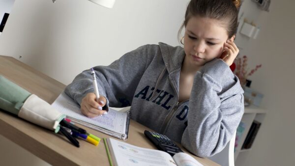 Eine Schülerin sitzt am Schreibtisch und schaut in ihre Schulhefte Foto: Studienkreis/B. Beuermann