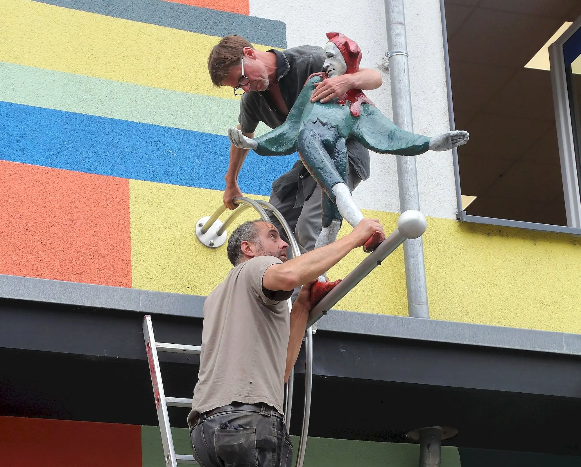 Die Skulptur für die Skulptur. - Till Eulenspiegel wurde gestern wieder auf seiner Metallstange an der Fassade der Neustadbilbiothek an der Köigsbrücker Straße angebracht. Foto: Ove Landgraf