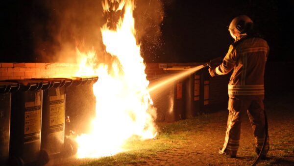 Ein Feuerwehrmann löscht einen brennenden Müllcontainer. Symbolbild - Foto: Roland Halkasch